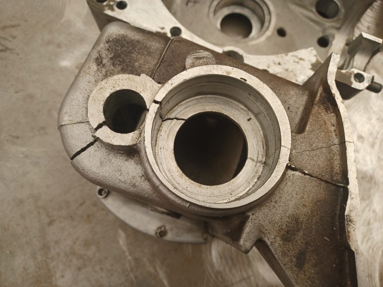 Close-up of a cracked metal engine housing part, showing multiple fractures radiating from a central circular opening—an ideal candidate for Specialist Aluminium Repair Work.